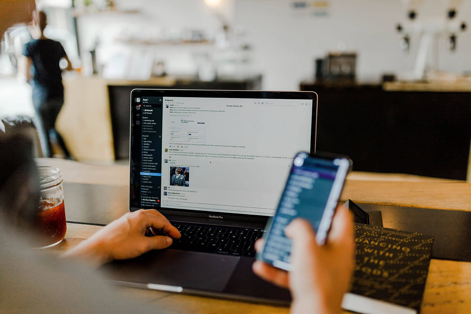 A man on computer and holding phone