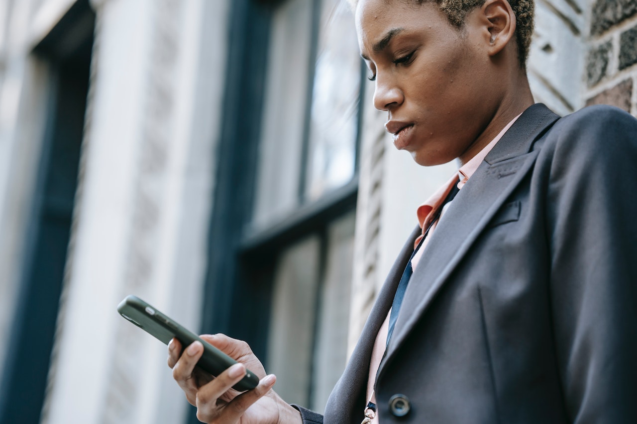 Business woman holding cellphone outside of workplace