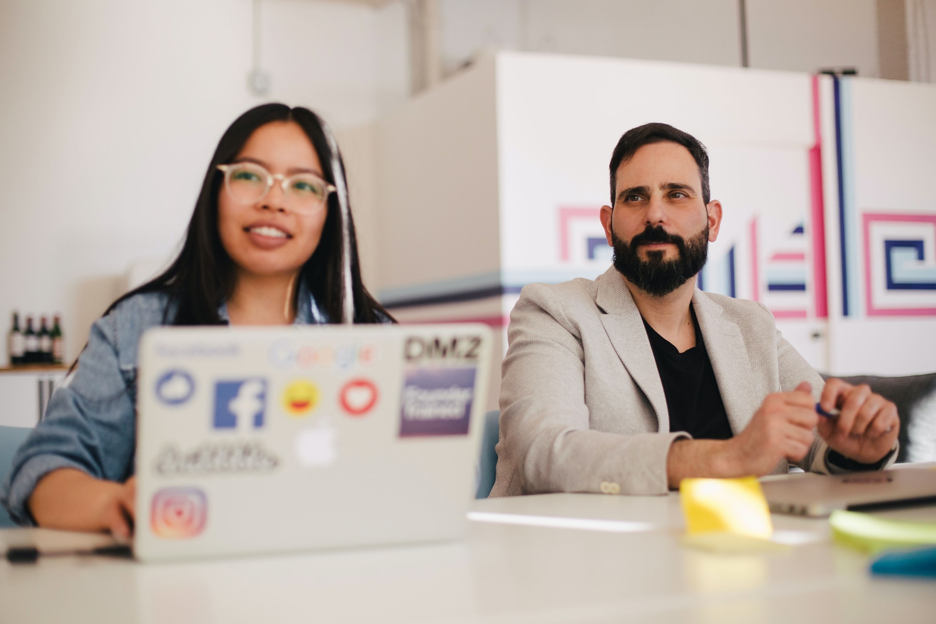 Two people sitting in a meeting looking towards someone or something off-camera.